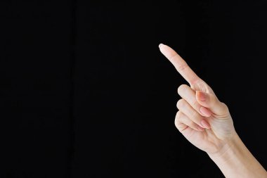 Pointing with index finger at studio of black background clipart