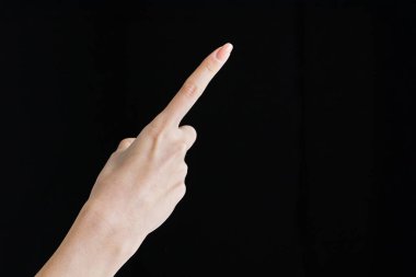 Pointing with index finger at studio of black background clipart