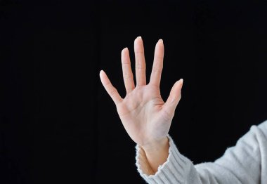 Avuçların açık ve siyah arka planda poz ver.