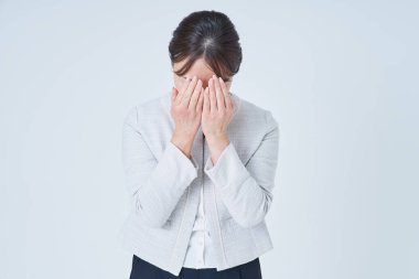 Yüzünü iki eliyle ve beyaz geçmişiyle örten bir kadın.