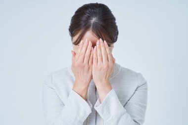 Yüzünü iki eliyle ve beyaz geçmişiyle örten bir kadın.