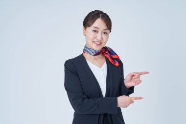 Takım elbiseli bir kadın parmak ve beyaz arka planda poz veriyor.