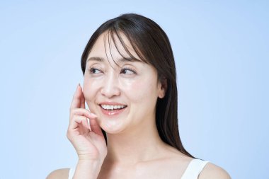 Orta yaşlı bir kadın tenine ve beyaz geçmişine dokunuyor.