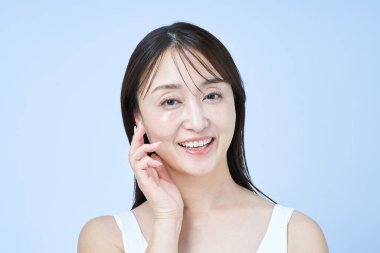 Orta yaşlı bir kadın tenine ve beyaz geçmişine dokunuyor.