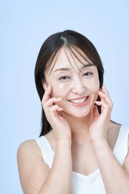 Orta yaşlı bir kadın tenine ve beyaz geçmişine dokunuyor.