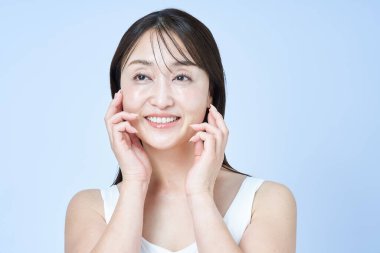 Orta yaşlı bir kadın tenine ve beyaz geçmişine dokunuyor.