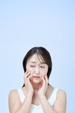 Yüzünde yorgun bir ifade olan orta yaşlı bir kadın cilt bakımı yapıyor ve beyaz bir geçmişi var.