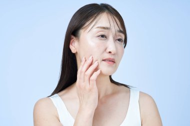 Yüzünde yorgun bir ifade olan orta yaşlı bir kadın cilt bakımı yapıyor ve beyaz bir geçmişi var.