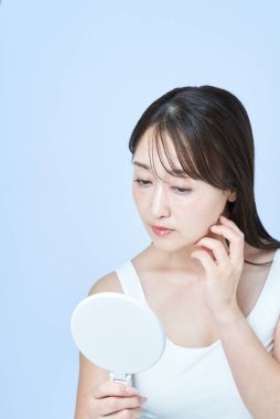 Yüzünde yorgun bir ifade olan orta yaşlı bir kadın cilt bakımı yapıyor ve beyaz bir geçmişi var.