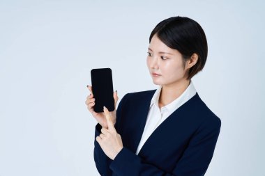 Akıllı telefon ve beyaz arka plan kullanan takım elbiseli bir kadın.