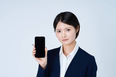 Akıllı telefon ve beyaz arka plan kullanan takım elbiseli bir kadın.