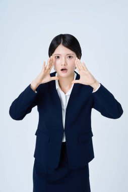 Bir iş kadını, iki eli yüzü ve beyaz arka planıyla bağırıyormuş gibi davranıyor.