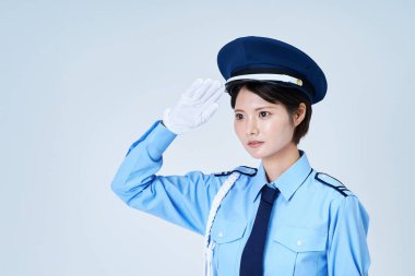 Güvenlik görevlisi üniformalı bir kadın selam veriyor ve beyaz bir geçmişi var.