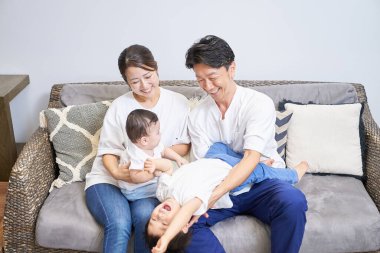 Parents and children relaxing on the sofa in a room clipart