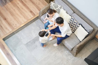 Parents and children relaxing on the sofa in a room clipart