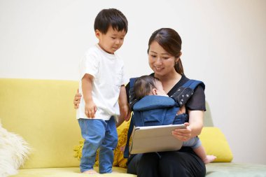 Mother and children sitting on sofa looking at tablet PC screen clipart