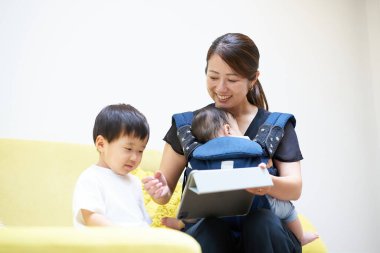 Mother and children sitting on sofa looking at tablet PC screen clipart