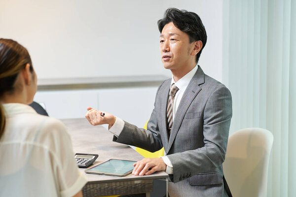 Мужчина в костюме разговаривает с женщиной в помещении