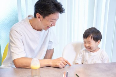 Bir adam ve bir çocuk gülümseyerek içeride oynuyorlar.