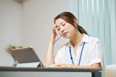   Bir odada bilgisayarla uğraşırken yorgun görünen bir kadın.                             