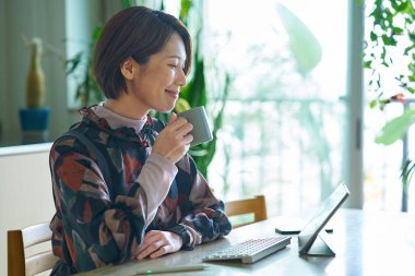 Bir kadın evde çalışırken bir kupayla mola veriyor.