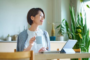 Bir kadın evde çalışırken bir kupayla mola veriyor.