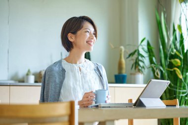 Bir kadın evde çalışırken bir kupayla mola veriyor.