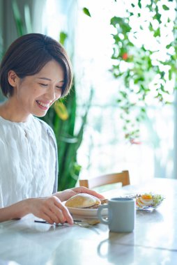 Odasında kahvaltı yapan orta yaşlı bir kadın.