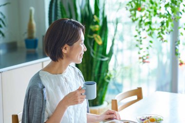 Odasında kahvaltı yapan orta yaşlı bir kadın.