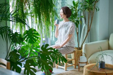 Etrafı saksılarla çevrili orta yaşlı bir kadın dinleniyor.