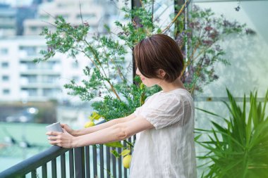 Balkonda bir kupa tutan rahat bir yüzü olan bir kadın.