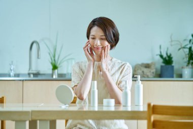 Odasında cilt bakımı yapan bir kadın.