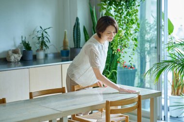 Odayı temizleyen orta yaşlı bir kadın.