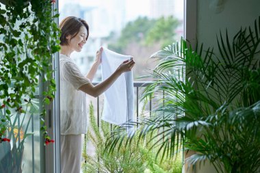 Çamaşırları balkona asan bir kadın.