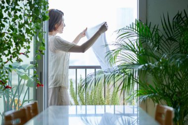 Çamaşırları balkona asan bir kadın.