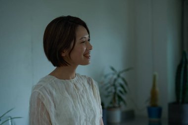 Loş bir odada duran orta yaşlı bir kadın.