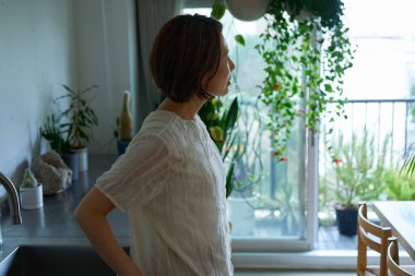 Loş bir odada duran orta yaşlı bir kadın.