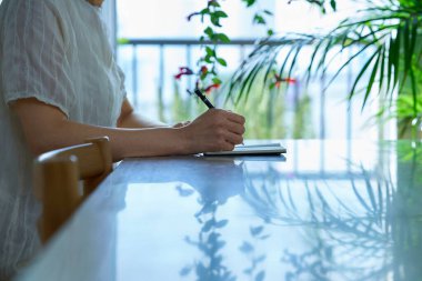 İçeriden not alan orta yaşlı bir kadın.