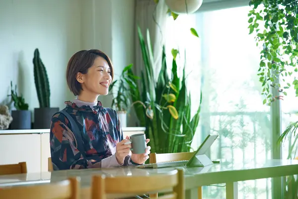 Bir kadın evde çalışırken bir kupayla mola veriyor.