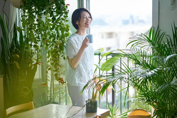 Etrafı saksılarla çevrili orta yaşlı bir kadın dinleniyor.