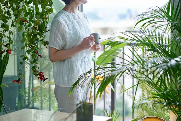 Etrafı saksılarla çevrili orta yaşlı bir kadın dinleniyor.