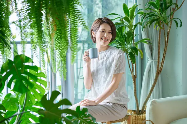 Etrafı saksılarla çevrili orta yaşlı bir kadın dinleniyor.