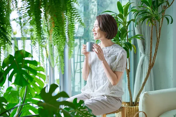 Etrafı saksılarla çevrili orta yaşlı bir kadın dinleniyor.