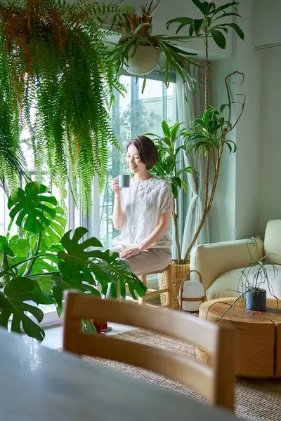 Etrafı saksılarla çevrili orta yaşlı bir kadın dinleniyor.