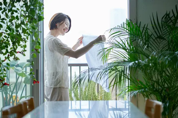 Çamaşırları balkona asan bir kadın.