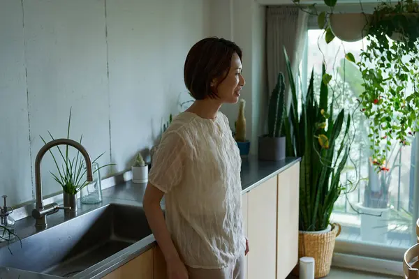 Loş bir odada duran orta yaşlı bir kadın.