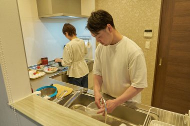 Bir çift mutfakta birlikte ev işi yapıyor.