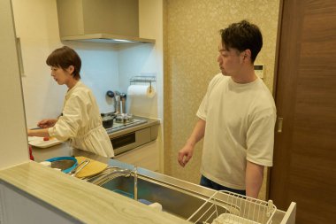 Bir çift mutfakta birlikte ev işi yapıyor.