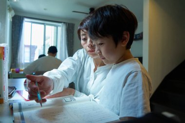 Evindeki odasında ders çalışan bir çocuk, annesi tarafından izleniyor.