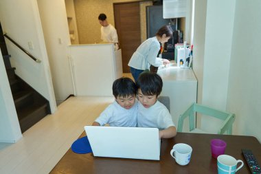 Evlerinde bilgisayar kullanan iki çocuk.